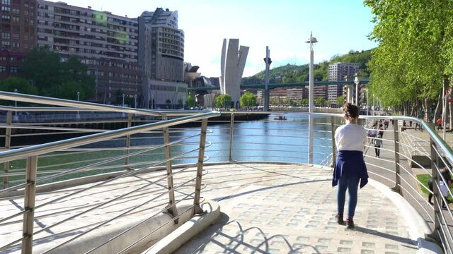 Little girl walking alone by the river in Bilbao city on sunny day