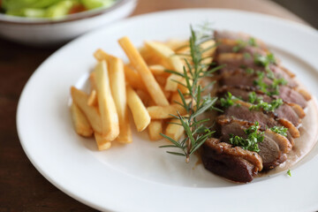 Duck magret confit with chips on wood table