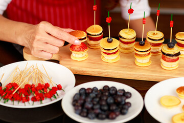 Closeup shot of delicious yummy healthy small mixed fruit banana strawberry blueberry chocolate pancake appetizer decorated with stick prepared by female chef or housewife.