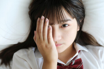 Portrait japanese school girl uniform sleep and look at camera in white tone bed room