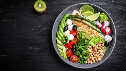 Fototapeta na wymiar Healthy salad bowl with avocado, asparagus, chickpeas, broccoli, radish, chicken, cucumber, tomatoes, olives, mozzarella on wooden background top view. Food and health