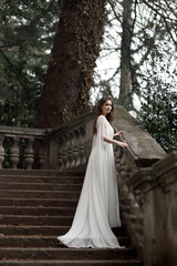 Wedding in an old villa in European style, trends 2021. The bride walks up the stairs of the villa overlooking the garden.