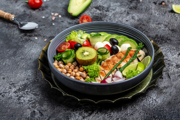 Bowl Buddha. avocado, asparagus, chickpeas, broccoli, radish, chicken, cucumber, tomatoes, olives, mozzarella on a stone background