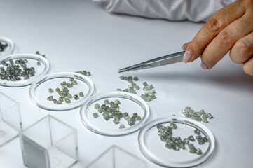 The process of manual sorting of diamonds. Gemstones are sorted by quality and weight and arranged...