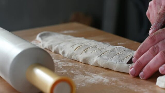 a rolling pin lies on the table a man prepares dough for chebureks makes balls of dough cuts the dough with a knife concept of homemade food. High quality 4k footage