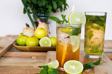 herbal healthy drinks cold lemon tea juice and lemon juice for health care with peppermint leaf and lemon slice on background wooden