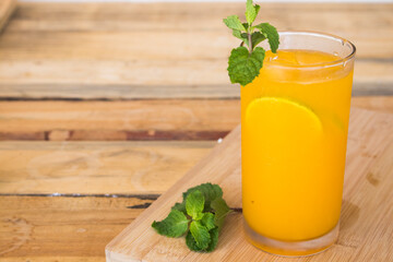 herbal healthy drinks cold orange juice for health care with peppermint leaf and lemon slice on background wooden
