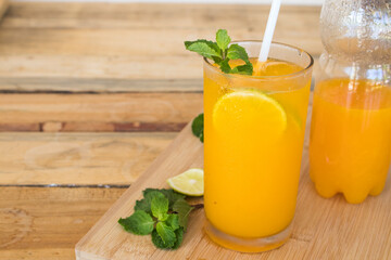 herbal healthy drinks cold orange juice for health care with peppermint leaf and lemon slice on background wooden