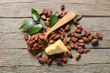 Spoon with cocoa beans on wooden background