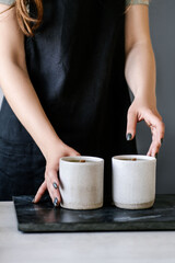 The girl pours wax into a gray concrete candle mold.