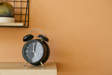 Shelf with alarm clock hanging on color wall