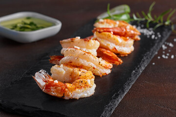 Fried scampi tails on slate serving board with herbs and sauce