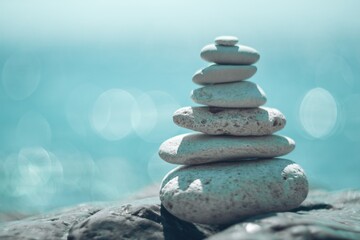 Pyramid stones on the seashore on a sunny day on the blue sea background. Happy holidays. Pebble beach, calm sea, travel destination. Concept of happy vacation on the sea, meditation, spa, calmness.