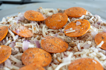 A closeup view of the toppings of a dairy-free and gluten-free frozen pizza, resting on a stove top.