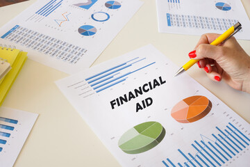 Business concept about FINANCIAL AID with sign on the printout with diagrams and tables.