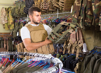 positive english man with flak jacket in hands in airsoft market