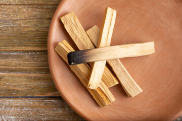 A top down view of a plate of palo santos incense burning sticks. 