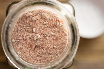 A top down closeup view of a condiment jar of kala namak rock salt.