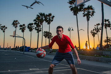 Basketball player training basketball on a court in Venice Beach.