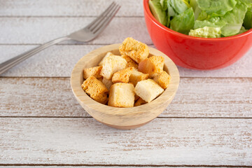 A view of a small bowl of croutons with a salad.