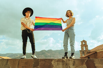 Amigos queer y bisexual flameando bandera LGTBQ en el cielo 