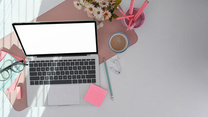 Female office desk with computer laptop, pencil holder, coffee cup and notebook.