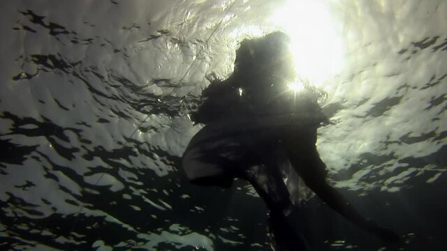 Young woman underwater model in white cloth on background of blue water. Concept of creativity and art of creating images.