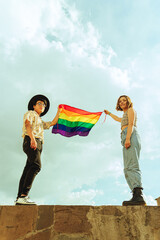 Amigos queer y bisexual flameando bandera LGTBQ en el cielo  - obrazy, fototapety, plakaty