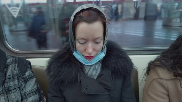 Woman in shawl in metro train reads something interesing