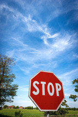 Close-up of a Stop Road Sign on blue sky with clouds and copy space. Rural scene, photography.