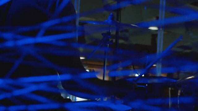 Drummer Playing Drums Seen Thru Blue Rope
