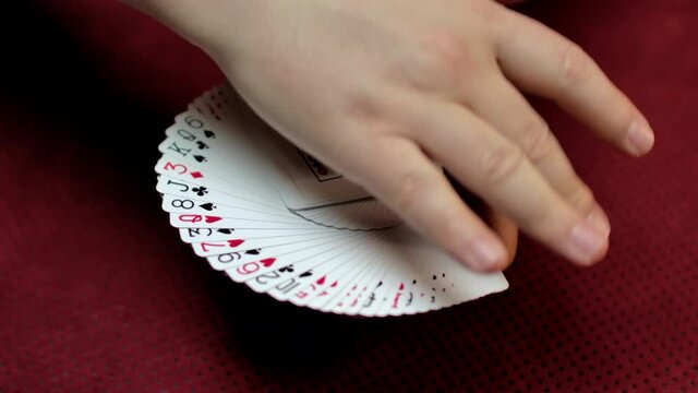 Slow motion close up of a magician spreading a deck of cards with the Jack of spades on top.