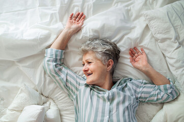 Top view of happy senior woman in bed at home, relaxing.