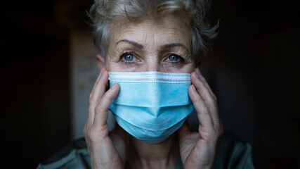 Depressed senior woman with face mask at home, coronavirus and mental health concept.