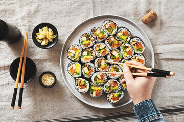 vegan sushi with tofu and avocado on a plate on a linen napkin. female hand