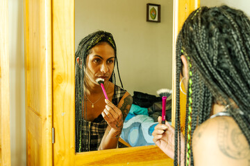 Mujer transgénero retocando su maquillaje frente al espejo de su habitación 