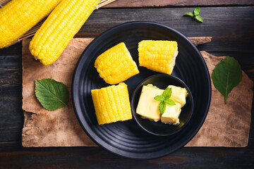 Sweet corn cob and butter in a bowl on wooden background, Top view