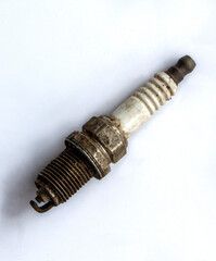  old used spark plug on white background. Broken auto part in a garage