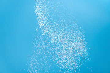 White powder explosion isolated on blue background. Flour sifting on a blue background. Explosive powder white