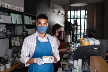 Portrait of waiter serving coffee in cafe, small business, coronavirus and new normal concept.