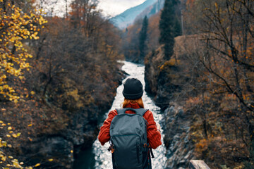 woman tourist stands on the bridge over the river or admires the nature landscape