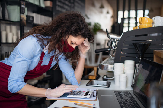 Frustrated coffee shop manager calculating figures in cafe, small business and new normal concept.