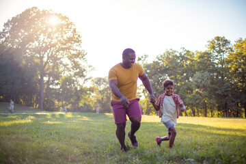  African American father and son in nature.  Son and dad running together.