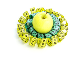 Measuring tape, twisted in a spiral, in the center of a yellow apple, isolated on a white background. Healthy and proper nutrition, calorie content. Fitness, diet, weight loss concept.
