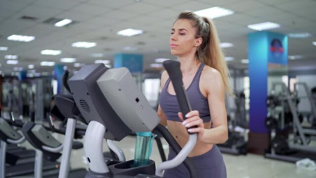 Young woman working out on orbi track at gym exercising