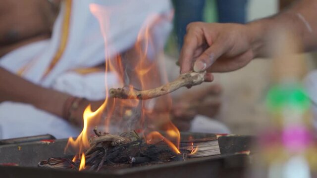 Man putting wooden stick in traditional Indian agni fire. Fire pit used in rituals of Indian culture & tradition. 