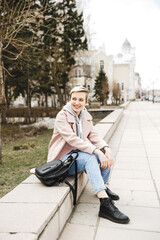 Attractive hipster blonde girl in a pink coat walks around beautiful authentic old town. The concept of freedom. creativity and inspiration