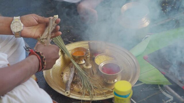 "Man performing Indian cultural & traditional ritual with wooden sticks, brass plates and vessels"