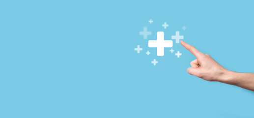 Male hand holding plus icon on blue background. Plus sign virtual means to offer positive thing...