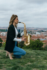 Young blonde girl playing the saxophone in a park